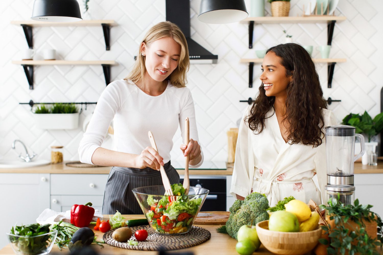 woman demonstrating healthy meal preparation to another woman in a kitchen. After nutrition consultation, Nutrition counseling can include healthy food demonstration.